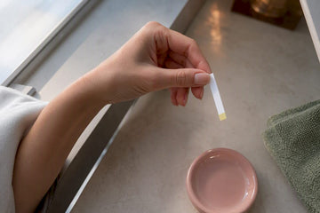 Hand using an at-home vaginal pH strip