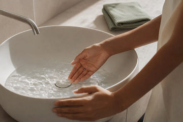 Hands testing warm water at basin