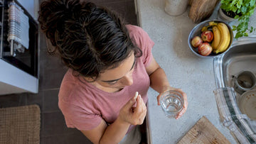 Woman taking a capsule with water